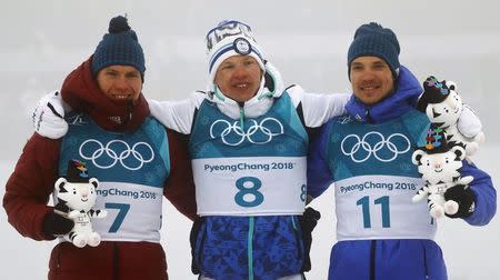 Cross-Country Skiing - Pyeongchang 2018 Winter Olympics - Men's 50km Mass Start Classic - Alpensia Cross-Country Skiing Centre - Pyeongchang, South Korea - February 24, 2018 - Gold medallist Iivo Niskanen of Finland is flanked by silver medallist Alexander Bolshunov, Olympic athlete from Russia, and bronze medallist Andrey Larkov, Olympic athlete from Russia, as they hold Soohorang Olympic plush mascots during the victory ceremony. REUTERS/Kai Pfaffenbach