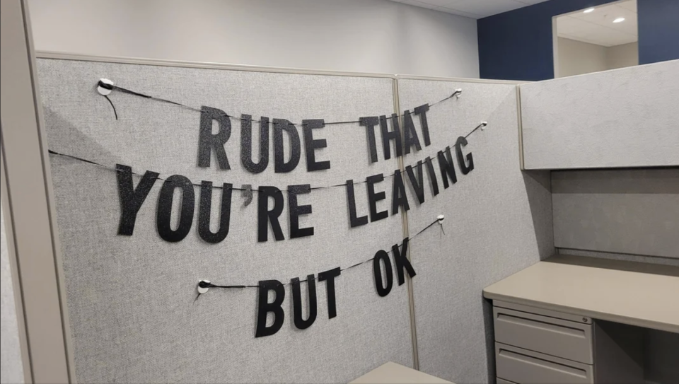 Decorative banner in an office cubicle reads, "Rude that you're leaving but ok"