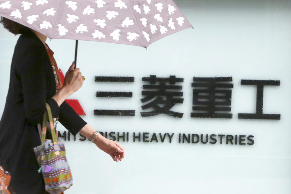 A woman walks past the company sign of the Mitsubishi Heavy Industries in Tokyo Tuesday, July 16, 2019. Colonial-era Korean laborers are seeking a court approval for the sales of local assets of their former Japanese company as it is refusing to compensate them. Lawyers for Koreans who worked for the Japanese company say they’ll soon request a South Korean court to authorize the sales of some of Mitsubishi’s seized assets in South Korea. (AP Photo/Koji Sasahara)