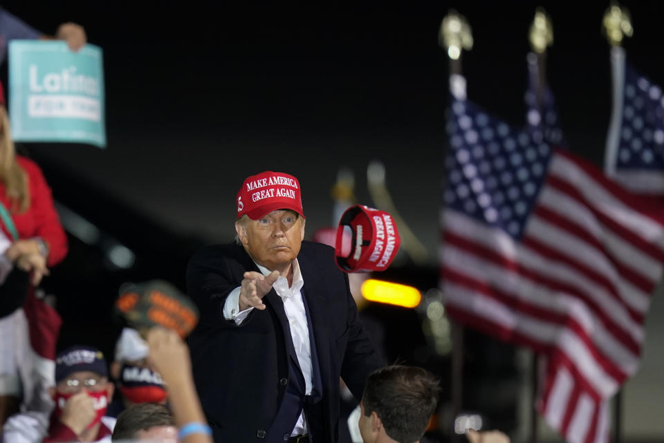 President Donald Trump throws a hat to a supporter during a campaign rally at Des Moines International Airport, Wednesday, Oct. 14, 2020, in Des Moines, Iowa. (AP Photo/Charlie Neibergall)