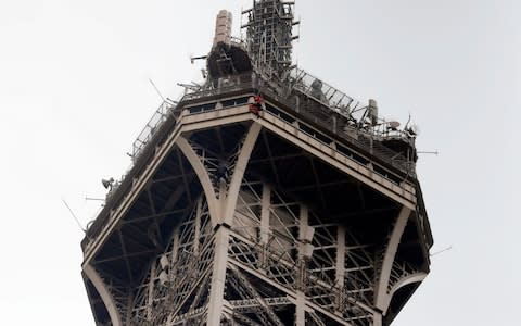 A rescue worker hangs from the Eiffel Tower following the intruder's ascent of the tourist attraction  - Credit: Michel Euler&nbsp;/AP