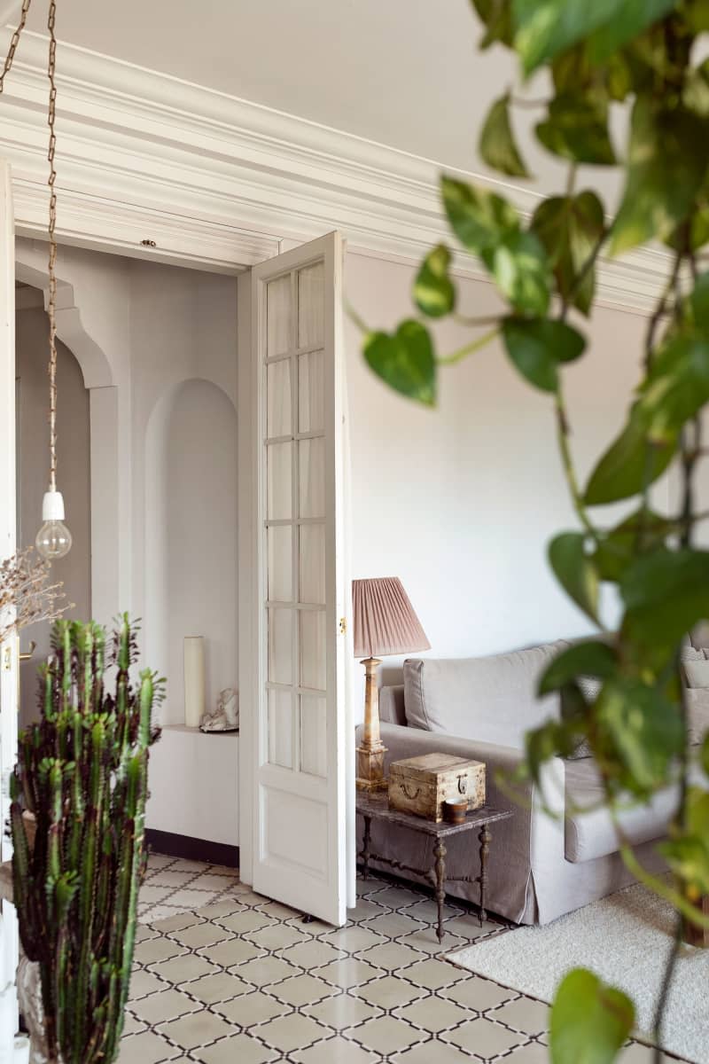 Plants line view of doorway in light neutral living area.