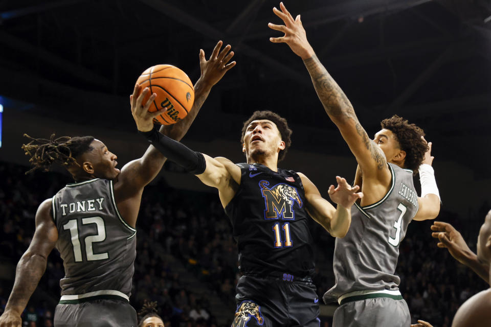 Memphis guard Jahvon Quinerly (11) goes up for a lay up between UAB guard Tony Toney (12) and forward Yaxel Lendeborg (3) during the first half of an NCAA college basketball game, Sunday, Jan. 28, 2024, in Birmingham, Ala. (AP Photo/ Butch Dill)