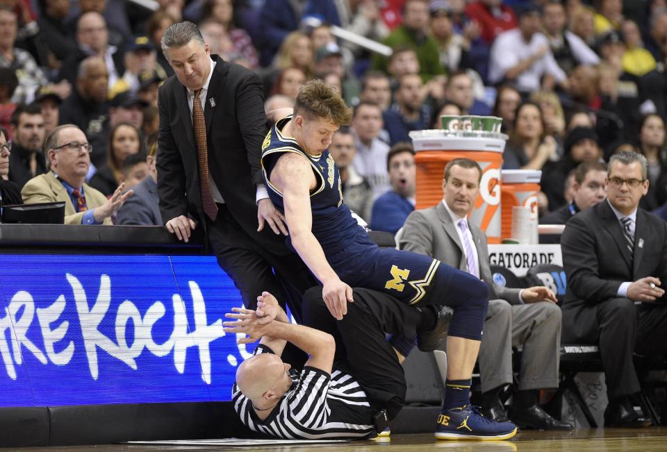 Michigan forward Moritz Wagner, top right, falls over an official next to Purdue head coach Matt Painter, top left, during the second half of an NCAA college basketball game in the Big Ten tournament against Purdue, Friday, March 10, 2017, in Washington. Michigan won 74-70 in overtime. (AP Photo/Nick Wass)