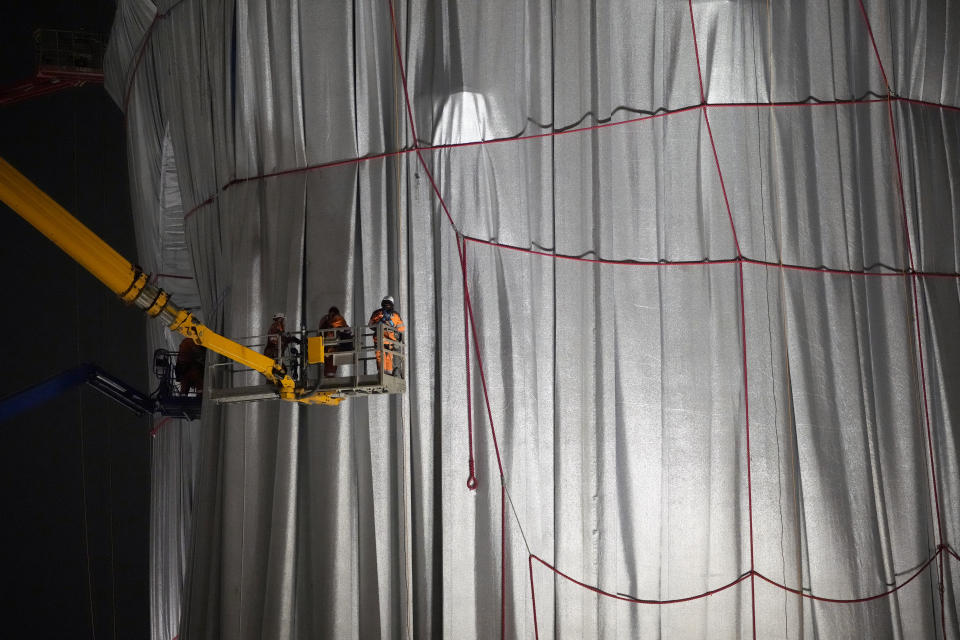 Workers wrap the Arc de Triomphe monument, Wednesday, Sept. 15, 2021 in Paris. The "L'Arc de Triomphe, Wrapped" project by late artist Christo and Jeanne-Claude will be on view from, Sept. 18 to Oct. 3. The famed Paris monument will be wrapped in 25,000 square meters of fabric in silvery blue, and with 3,000 meters of red rope. (AP Photo/Francois Mori)