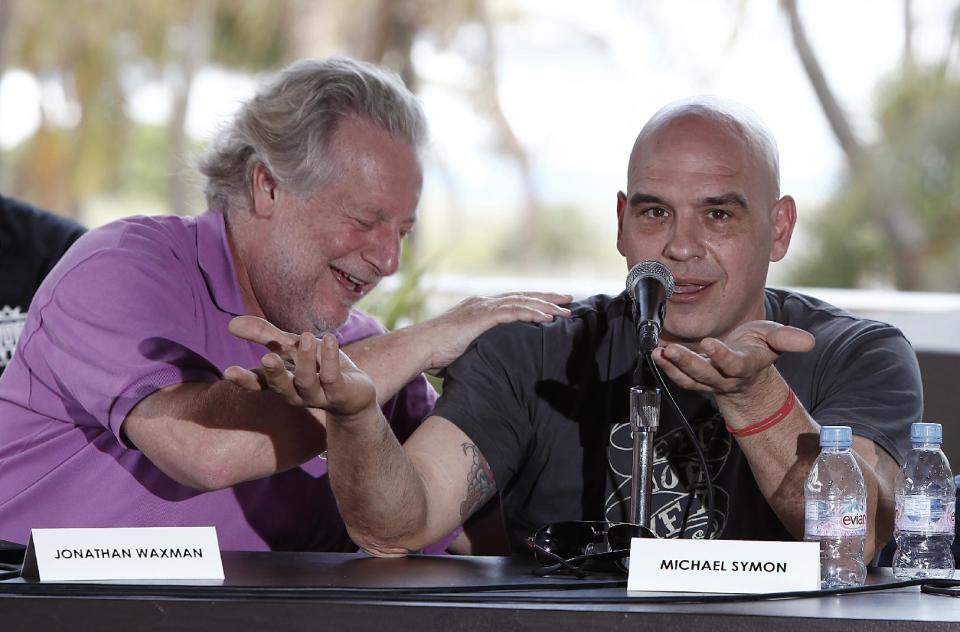 Celebrity chefs Jonathan Waxman, left, and Michael Symon laugh during a panel discussion about the experience of competing on TV cooking competitions, Saturday, Feb. 25, 2012 in Miami. (AP Photo/Carlo Allegri)