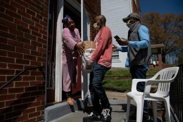 Anthony Lorenzo Green (R) and Bernard Stevenson (C) deliver groceries to a woman in Washington during the coronavirus pandemic (AFP Photo/NICHOLAS KAMM)