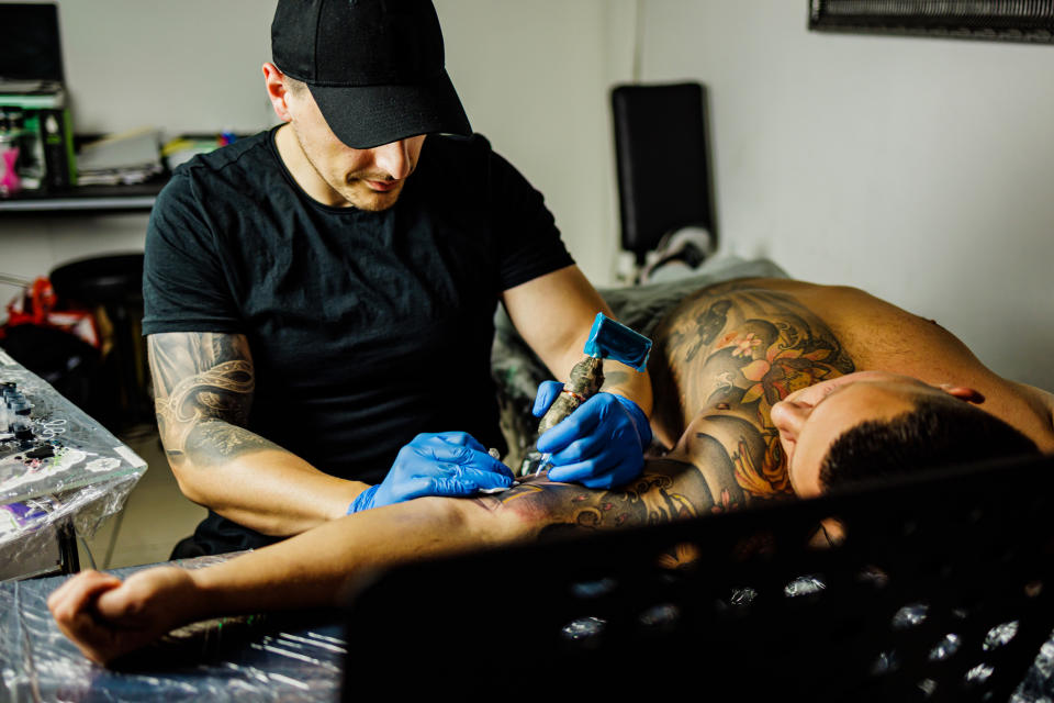 Tattoo artist working on a client's arm both are focused on the tattooing process