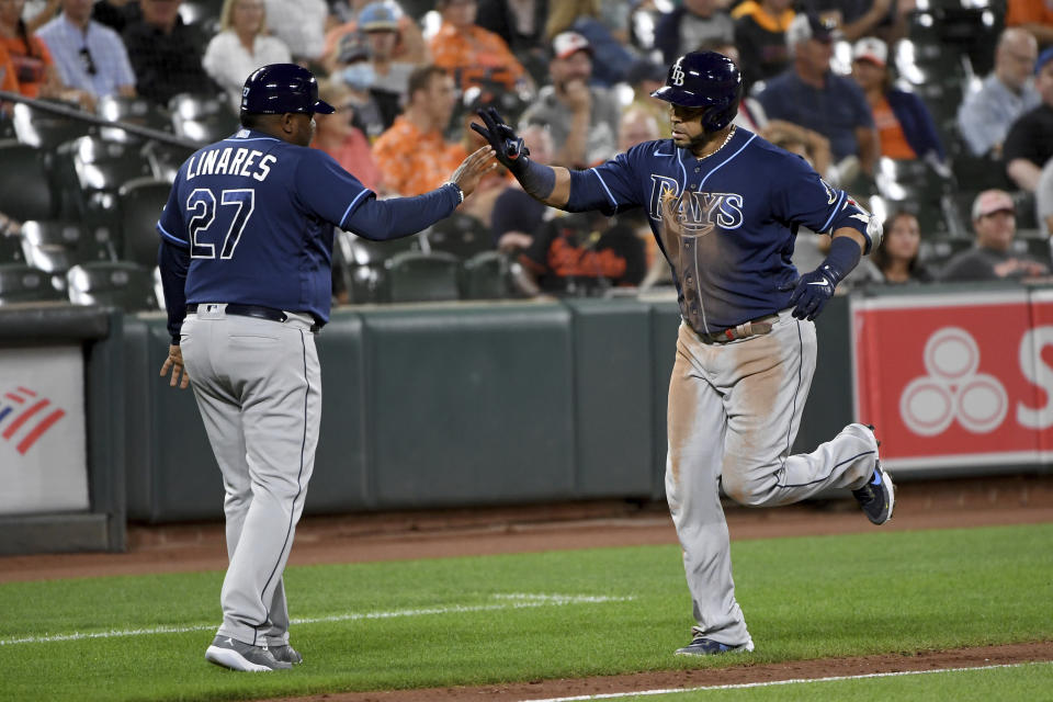 Tampa Bay Rays' Nelson Cruz celebrates with third base coach Rodney Linares (27) after hitting a two-run home run against the Baltimore Orioles during the fifth inning of a baseball game Saturday, Aug. 7, 2021, in Baltimore. (AP Photo/Will Newton)