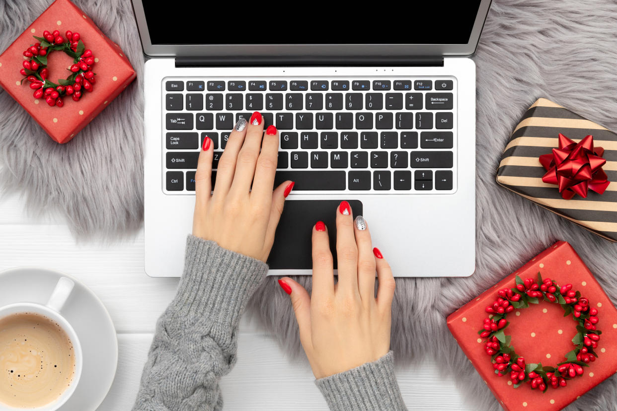 Womans hands with trendy red manicure typing on the keyboard. Christmas new year fashion clothes and accessories. Online shopping sale concept