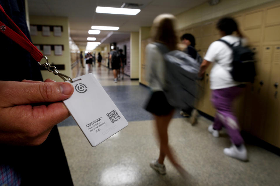 FILE - Brent Kiger, Olathe Public Schools' director of safety service, displays a panic-alert button while students at Olathe South High School rush between classes, Aug. 19, 2022, in Olathe, Kan. The district introduced the buttons, which allow staff to trigger a lockdown that will be announced with flashing strobe lights, a takeover of staff computers and a prerecorded intercom announcement, at the start of this school year as part of $2.1 million plan to make district schools more secure. In the wake of a deadly elementary school shooting in Tennessee earlier this week, state lawmakers across the country are moving forward with school safety measures. (AP Photo/Charlie Riedel, File)