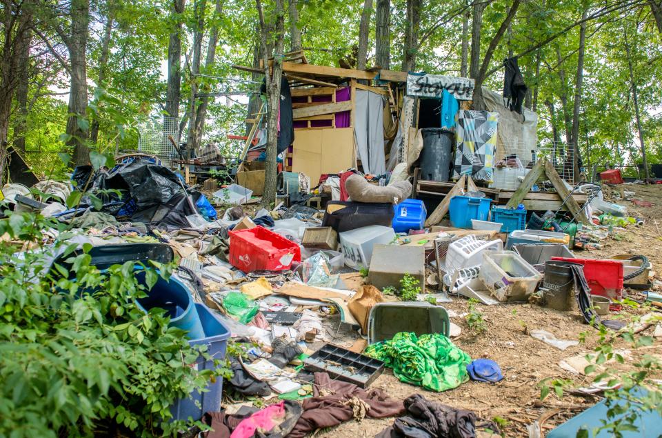 Piles of clothing, plastic tubs and other items surround a makeshift dwelling at a homeless encampment near the Landmark Recreation Center in Peoria.