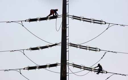 Employees of K-Electric fix cables on a power transmission tower in Karachi, Pakistan, August 22, 2016. REUTERS/Akhtar Soomro
