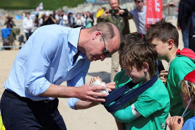 Prince William signs the cast of Felix Kanes, a member of Holywell Bay Surf Life Saving Club (Toby Melville/PA)