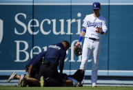 Los Angeles Dodgers right fielder Cody Bellinger, right, waves to a fan that ran out to him as she is handcuffed during the ninth inning of a baseball game against the Colorado Rockies, Sunday, June 23, 2019, in Los Angeles. (AP Photo/Mark J. Terrill)