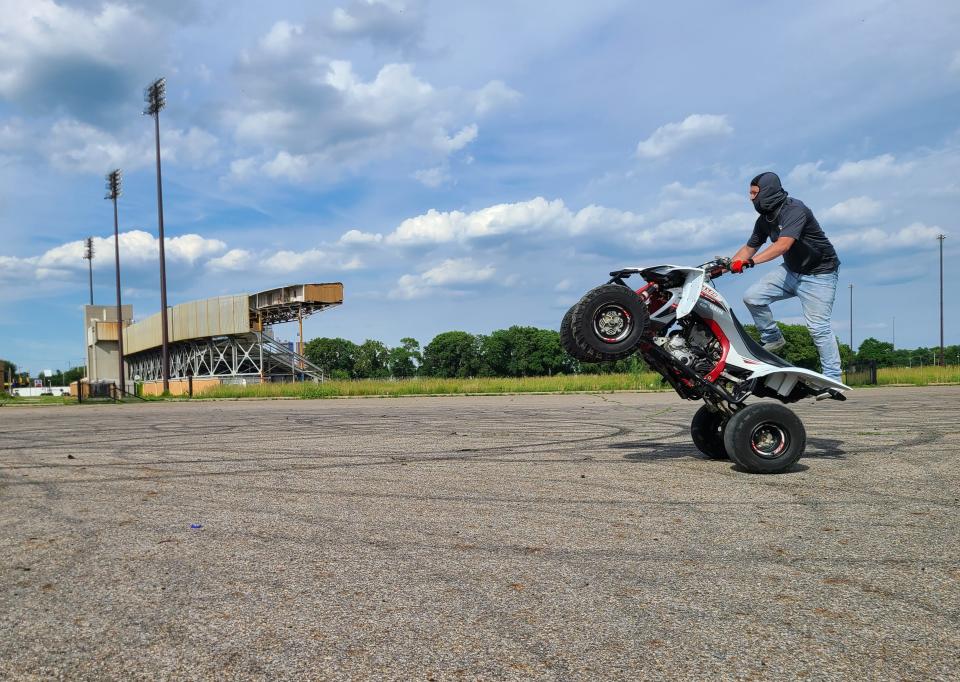 An ATV rider does a wheelie in the parking lot of former Cooper Stadium.