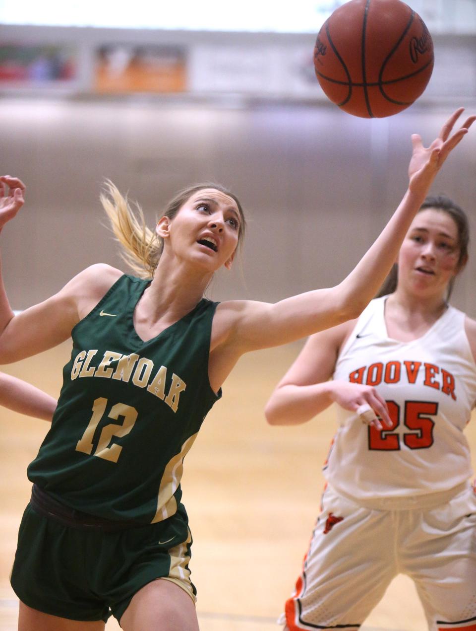 Kiley Dyrlund, 12, of of GlenOak reaches for a rebound as Lauren Rose, 25, of Hoover looks on during their game at Hoover on Saturday.