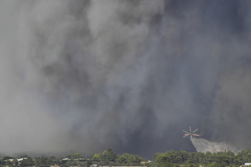 A helicopter of the Greek Fire Service drops water during a wildfire that broke out in Tatoi, northern Athens, Greece, Tuesday, Aug. 3, 2021. The Greek Fire Service maintained an alert for most of the country Tuesday and Wednesday, while public and some private services shifted operating hours to allow for afternoon closures. (AP Photo/Michael Varaklas)