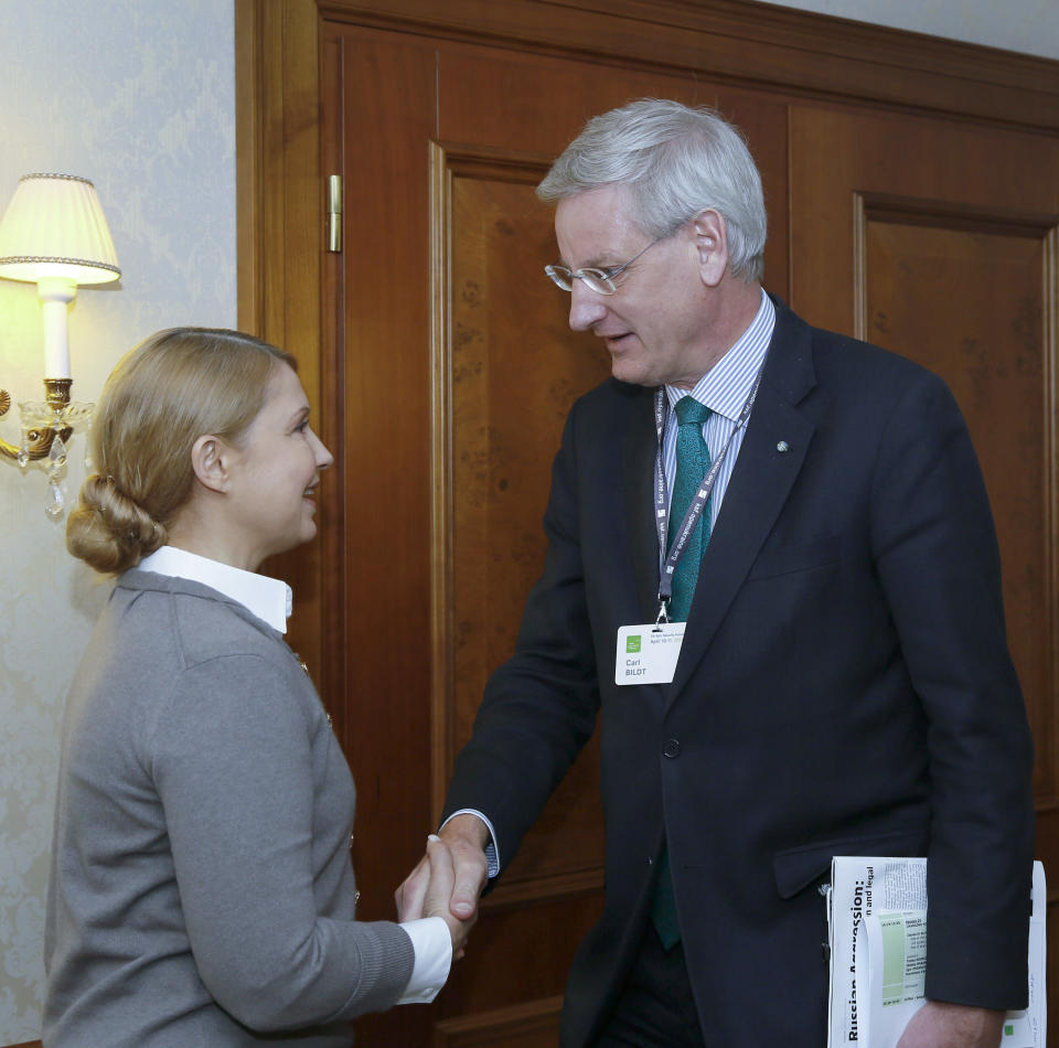 Former Ukrainian Prime Minister Yulia Tymoshenko, left, shakes hands with Sweden's Foreign Minister Carl Bildt in Kiev, Ukraine, Friday, April 11, 2014. (AP Photo/Olexander Prokopenko, Pool )