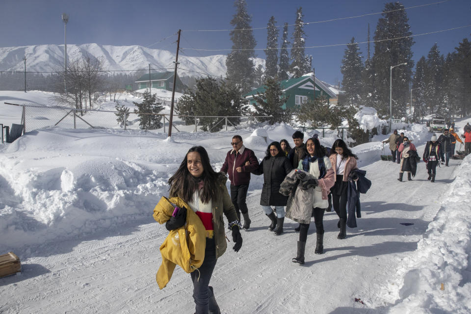 Indian tourists walk on a snow covered road in Gulmarg, northwest of Srinagar, Indian controlled Kashmir, Monday, Jan. 11, 2021. Snow this winter has brought along with it thousands of locals and tourists to Indian-controlled Kashmir's high plateau, pastoral Gulmarg, which translates as “meadow of flowers." (AP Photo/ Dar Yasin)