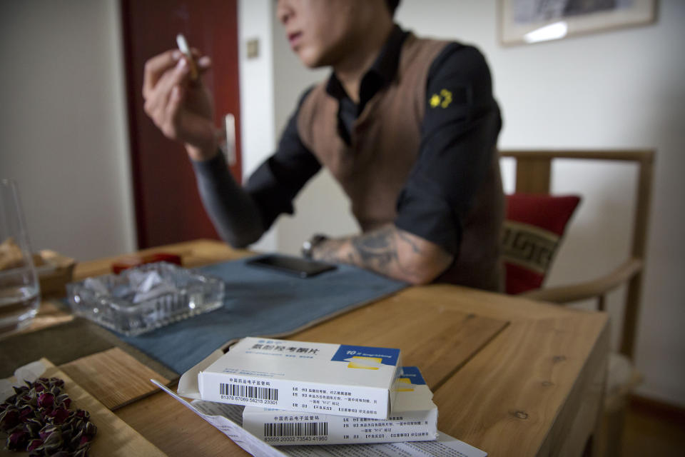 In this March 28, 2019, photo, Yin Hao, who also goes by Yin Qiang, talks about his addiction while sitting near boxes of Tylox pills he earlier purchased illicitly in a tea house in Xi'an, northwestern China's Shaanxi Province. Officially, pain pill addiction is an American problem, not a Chinese one. But people in China have fallen into opioid addiction the same way many Americans did, through a doctor's prescription. And despite China's strict regulations, online trafficking networks, which facilitated the spread of opioids in the U.S., also exist in China. (AP Photo/Mark Schiefelbein)
