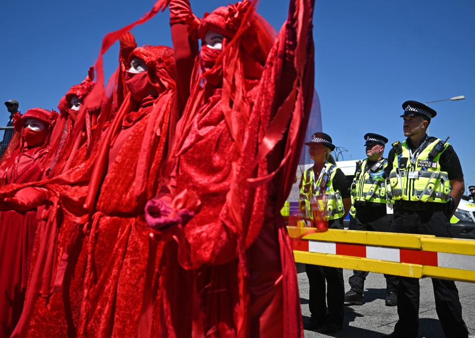 Police monitor the 'Red Brigade' group from the Extinction Rebellion environmental activists as they protest in the streets of Falmouth, Cornwall during the G7 summit on June 12, 2021.