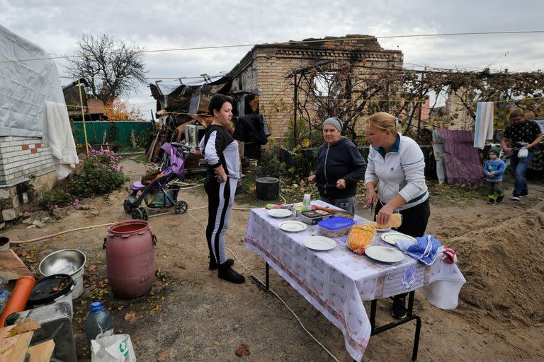 Mujeres preparan una mesa cerca de una casa destruida como resultado de los bombardeos en el pueblo de Gorenka, región de Kiev, el 29 de octubre de 2022