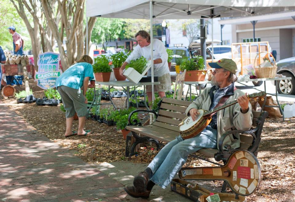 This undated image released by Visit Pensacola shows a street musician performing as a vendor sets out his wares at the Palafox Market in downtown Pensacola. For decades, Pensacola’s quiet downtown was overlooked by tourists lured instead to the sugary white sands of the nearby beaches. But a major push to revitalize the long-neglected business and office district is slowly bringing visitors back downtown. (AP Photo/Visit Pensacola)