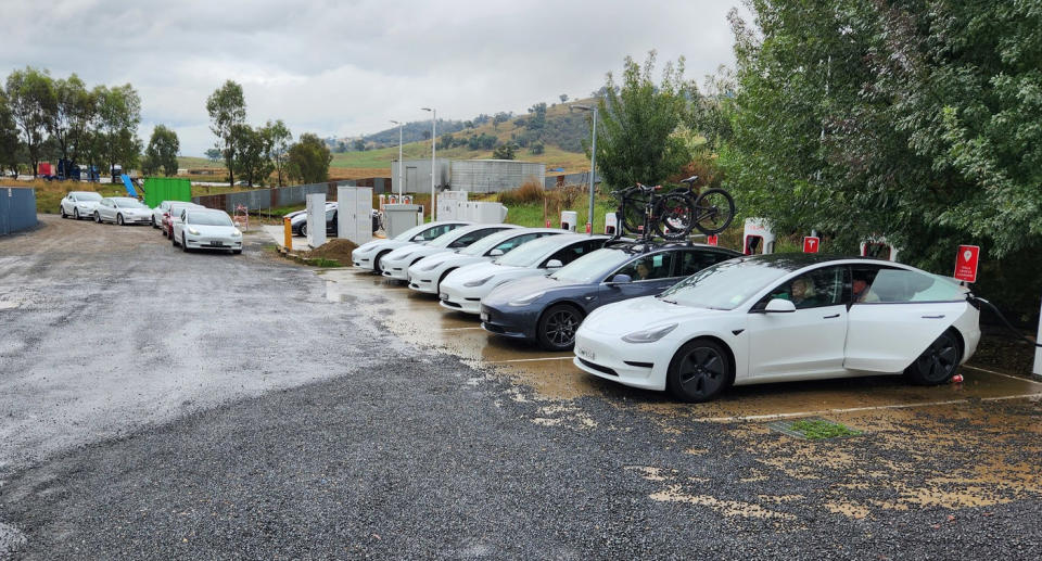 A row of Teslas at an EV charging station.