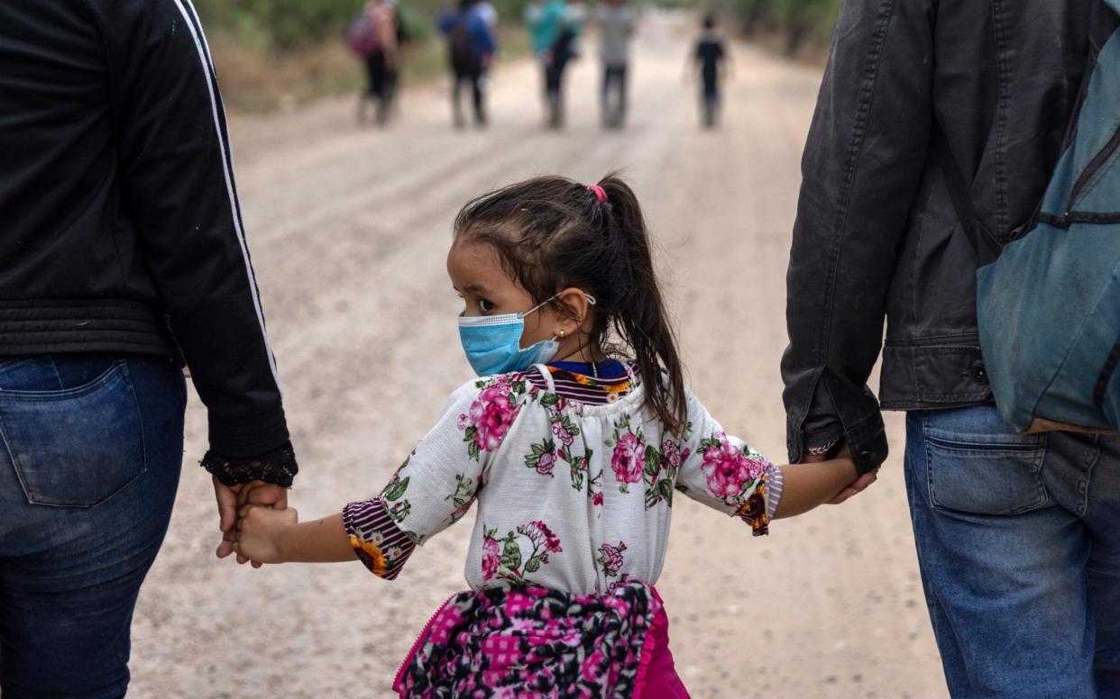 An immigrant child glances back towards Mexico after crossing the border into the United States  - Getty