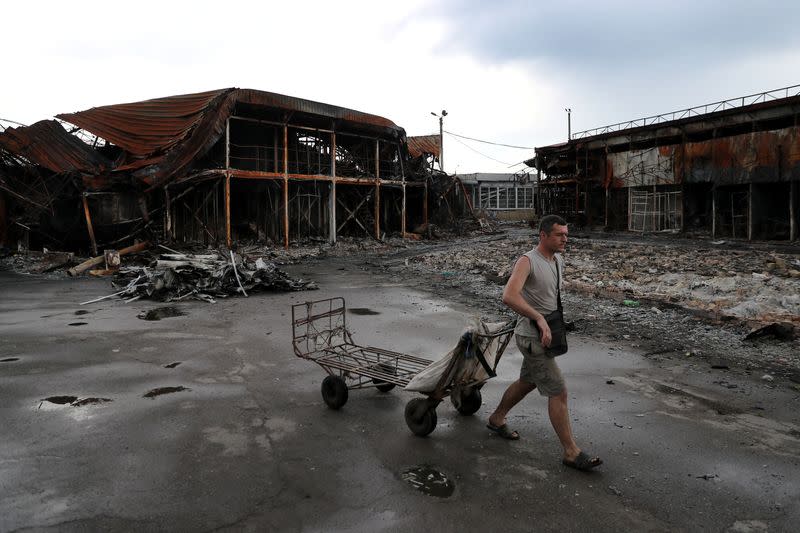 Un hombre tira de un carro en el mercado bombardeado de Barabashovo, en medio del ataque de Rusia a Ucrania, en Járkov, Ucrania