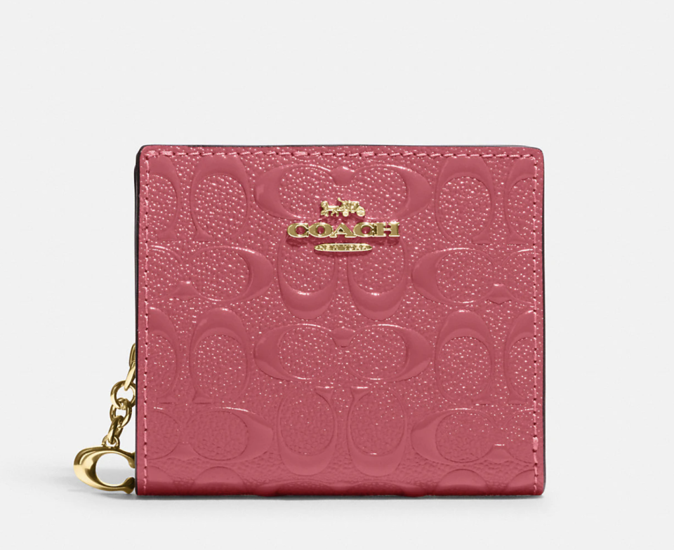 Snap Wallet In Signature Leather in pink with gold hardware. (Photo via Coach Outlet)