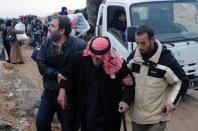 Residents of the industrial city of Adra, northeast of Damascus, help an elderly man on December 30, 2013, as they evacuate the area due to fighting between government troops and opposition forces