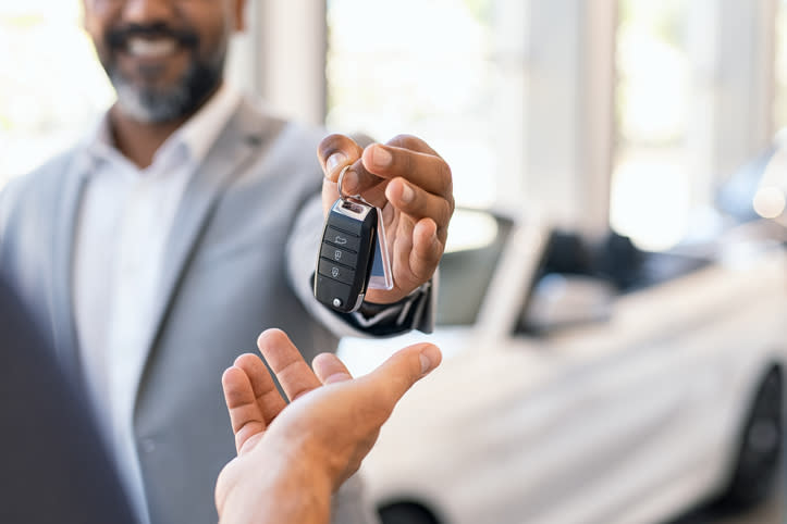 A salesman handing new car keys to a customer.