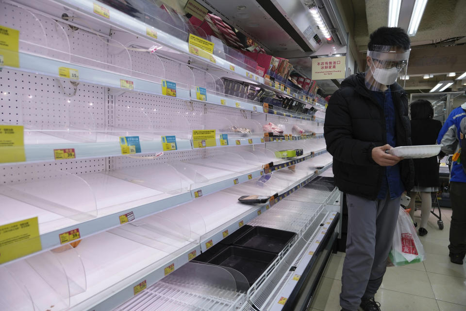 A man wearing a protective mask stands next to empty shelves of meat as residents worry about a shortage of fresh food, at a supermarket in Hong Kong Monday, Feb. 28, 2022. Hong Kong on Monday reported a record-high 34,466 infections, with health authorities saying that a lockdown has not been ruled out as fatalities continued to climb. (AP Photo/Vincent Yu)