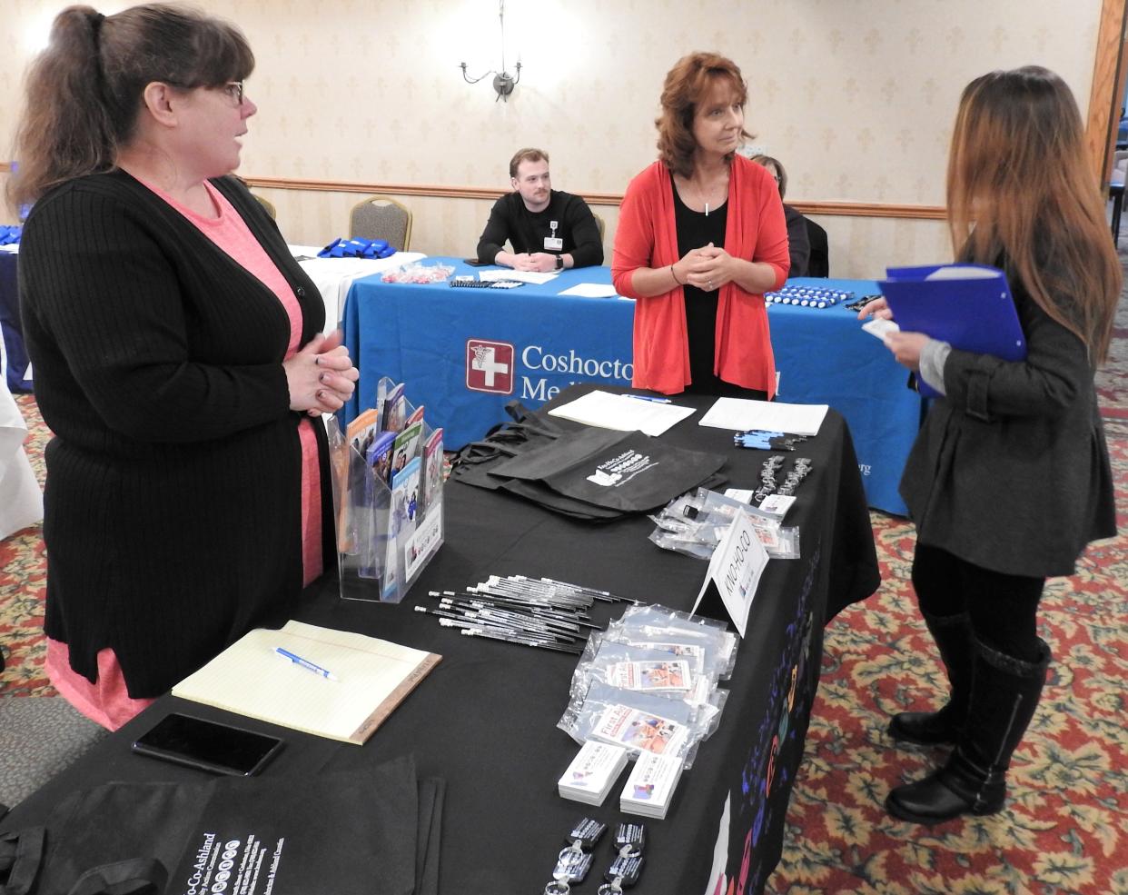 Jenny Collins and Donna Denning of Kno-Ho-Co-Ashland Community Action Commission speak with a potential job seeker at a job fair. The agency said it's looking for home delivery drivers, weatherization technicians and two office workers.