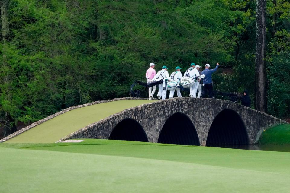 Sam Bennett, Brooks Koepka and Jon Rahm cross the Hogan Bridge on the 12th hole during the third round of the Masters in 2023.