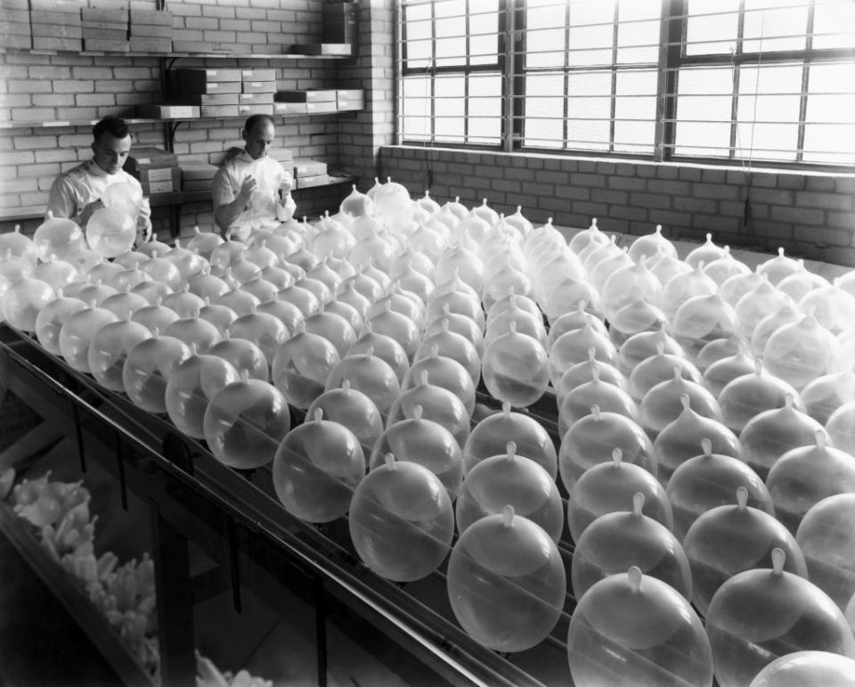 Two workers inspecting a large number of glass bulbs on a factory table