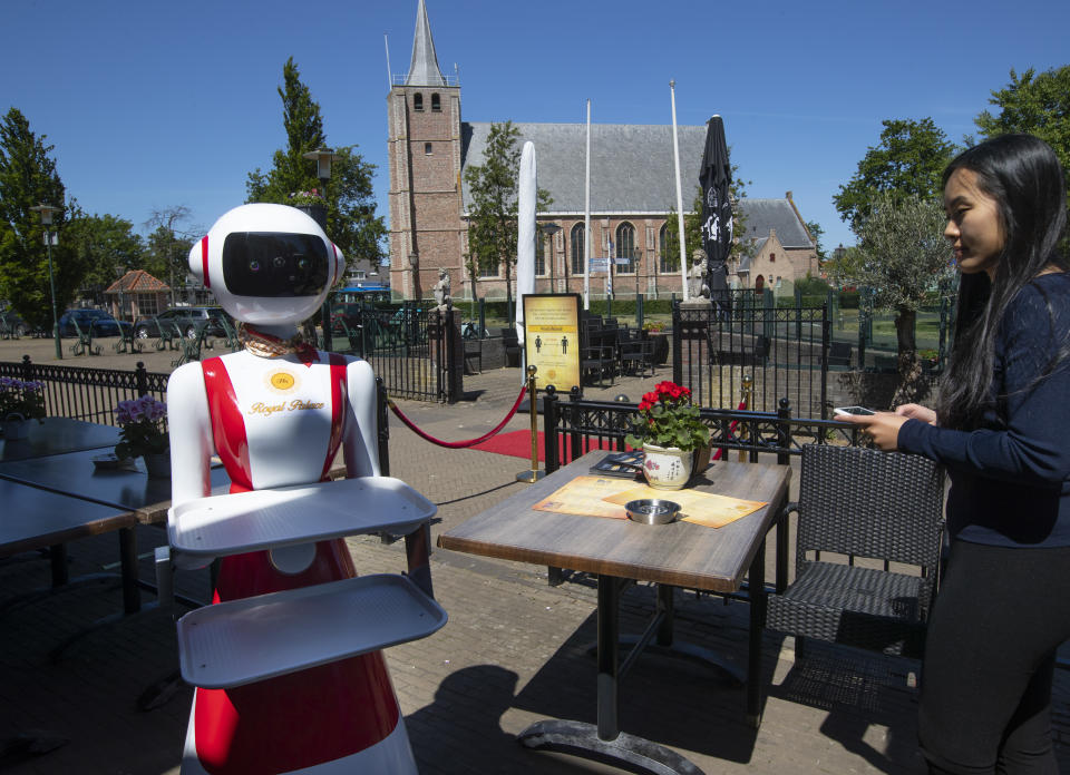 Leah Hu uses a tablet to demonstrate the use of a robot for serving purposes or for dirty dishes collection, as part of a tryout of measures to respect social distancing and help curb the spread of the COVID-19 coronavirus, at the family's Royal Palace restaurant in Renesse, south-western Netherlands, Wednesday, May 27, 2020. (AP Photo/Peter Dejong)