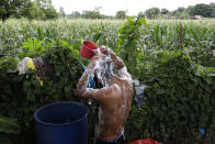 Ronnel Manjares takes a bath outside his house in Tanauan, Batangas province, Philippines, Wednesday, July 15, 2020. His 16-day-old son Kobe Manjares was heralded as the country's youngest COVID-19 survivor. But the relief and joy proved didn't last. Three days later, Kobe died on June 4 from complications of Hirschsprung disease, a rare birth defect. (AP Photo/Aaron Favila)