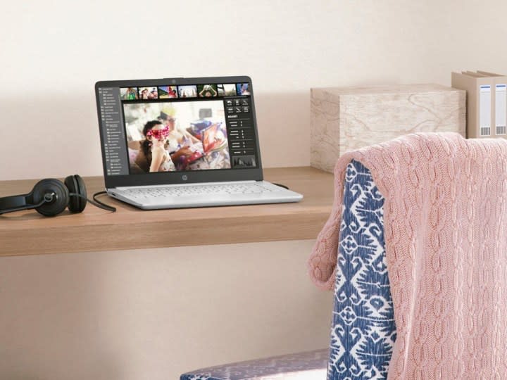 The HP 14-inch laptop on a small desk with some headphones.