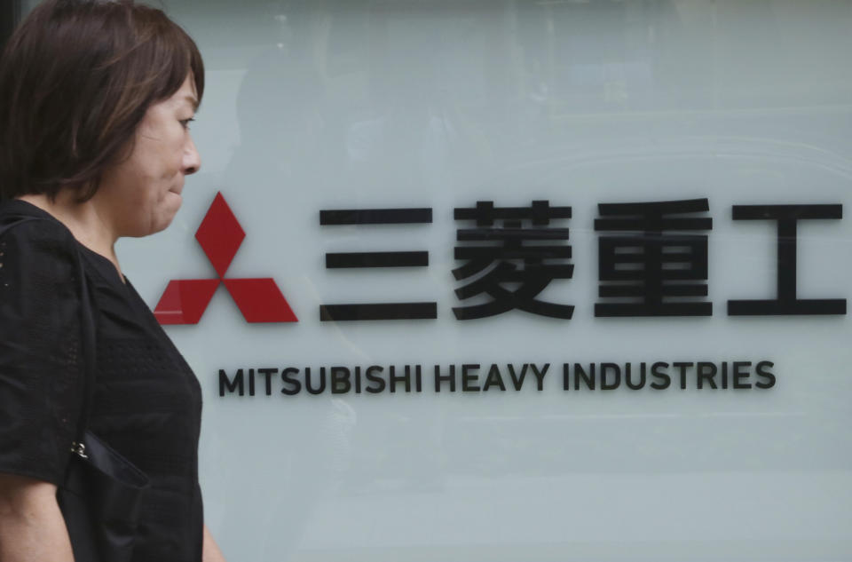 A woman walks past the company sign of the Mitsubishi Heavy Industries in Tokyo, Tuesday, July 23, 2019. Colonial-era Korean laborers have formally registered their request with a South Korean court to get its approval for the sale of local assets of their former Japanese employer. (AP Photo/Koji Sasahara)