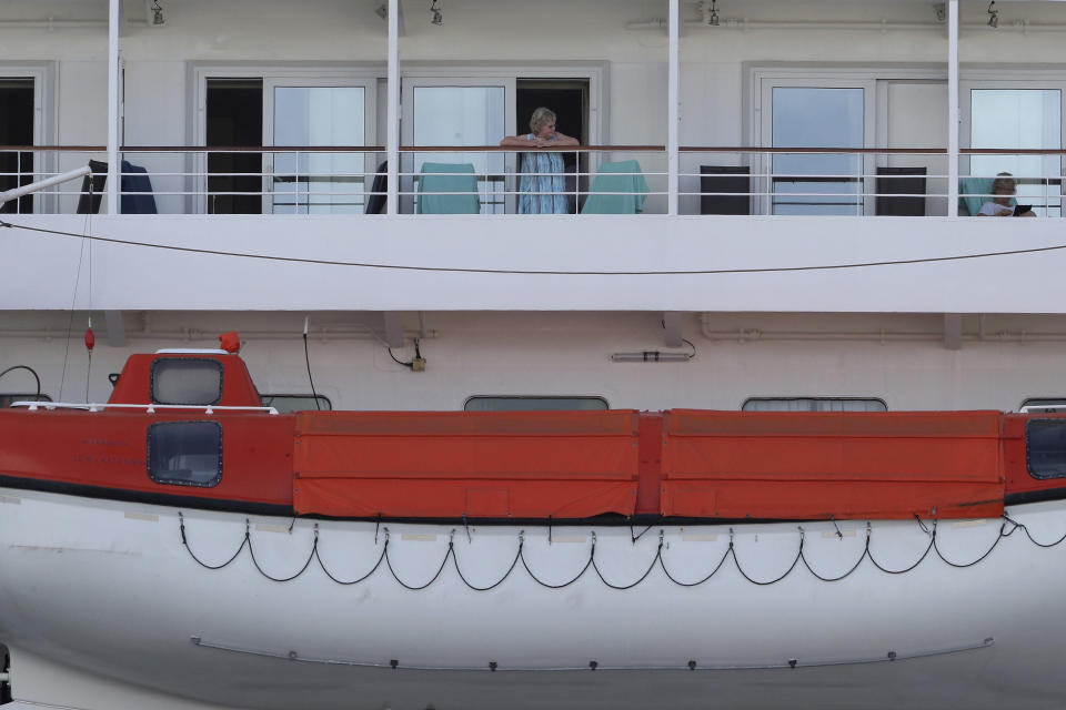 In this Friday, March 27, 2020, photo, passengers are seen on the cruise ship Artania docked at Fremantle harbour in Fremantle, Australia. Authorities were still hoping to fly 800 cruise ship passengers from Australia to Germany on the weekend, but a sharp overnight rise in cases of the new coronavirus on board brought severe complications for the repatriation mission. (Richard Wainwright/AAP Image via AP)