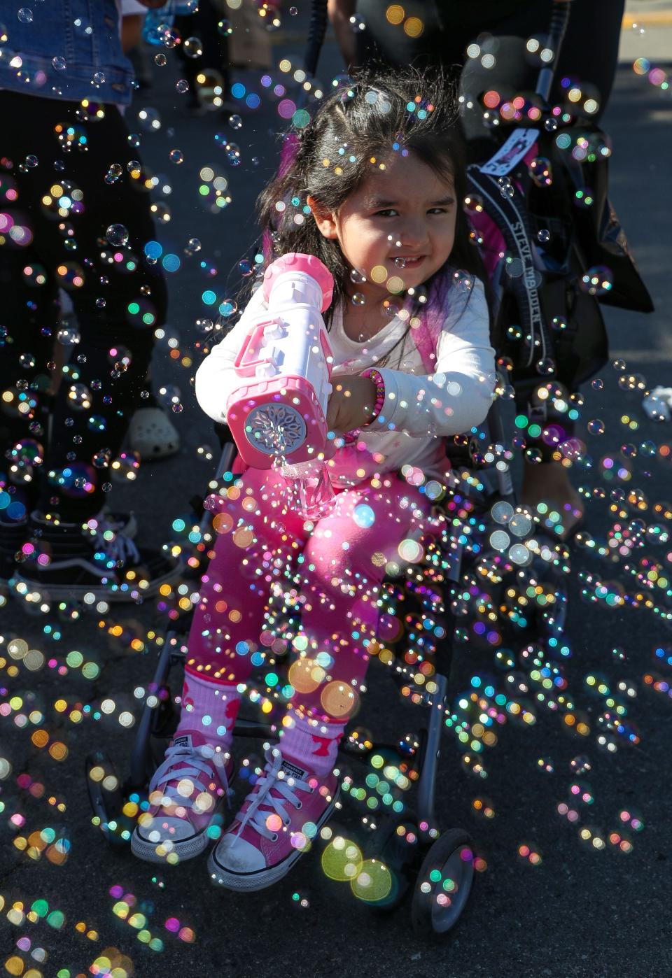 Two-year-old Melahni Martinez has a blast with her bubble gun at the Indio Tamale Festival at Miles Park in Indio, Calif., Dec. 2, 2023.