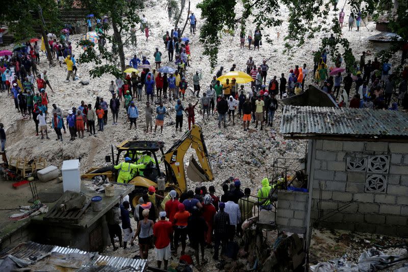 Residents look at workers at an area affected by the passage of Tropical Storm Laura, in Port-au-Prince