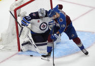 Winnipeg Jets goaltender Connor Hellebuyck, left, stops a shot by Colorado Avalanche right wing Valeri Nichushkin during the third period of Game 3 of an NHL hockey Stanley Cup first-round playoff series Friday, April 26, 2024, in Denver. (AP Photo/David Zalubowski)