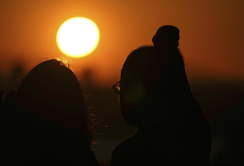 A couple watches the sun set in Medina, Wash.