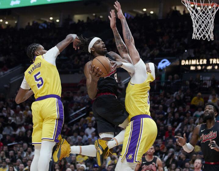 Portland Trail Blazers forward Jerami Grant, center, shoots between Los Angeles Lakers forward Cam Reddish, left, and forward Anthony Davis during the second half of an NBA basketball In-Season Tournament game in Portland, Ore., Friday, Nov. 17, 2023. (AP Photo/Craig Mitchelldyer)