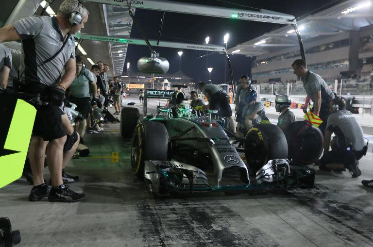 Mechanics change tires on the car of Mercedes-AMG's British driver Lewis Hamilton in the pits during the second practice session at the Yas Marina circuit in Abu Dhabi ahead of the Abu Dhabi Formula One Grand Prix on November 21, 2014