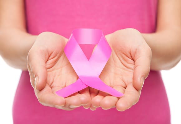 Woman holding pink breast cancer awareness ribbon in hands